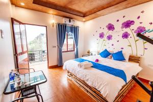 1 dormitorio con 1 cama con flores púrpuras en la pared en Khai Yen Tam Coc Hostel, en Ninh Binh