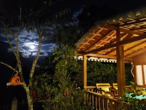 uma pérgola de madeira com uma mesa e cadeiras num pátio em Pousada Caminho do Escorrega em Visconde de Mauá