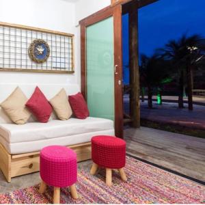 uma sala de estar com um sofá branco e dois bancos cor-de-rosa em Chale´Ville Charme 501 em Luís Correia