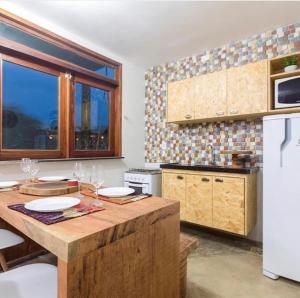 uma cozinha com uma mesa de madeira e um frigorífico branco em Chale´Ville Charme 501 em Luís Correia
