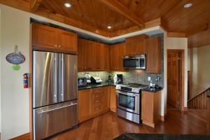 a kitchen with wooden cabinets and a stainless steel refrigerator at Blue Mountain-Luxurious BlueSki George Chalet, Hot Tub, Pool, Gas Fireplace in Blue Mountains