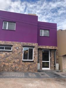 a purple building with a stone wall at Hotel boutique urku wasi in Humahuaca