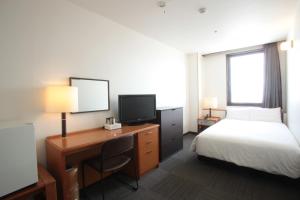 函館市にあるホテル函館ロイヤル(BBHホテルグループ)のベッド、デスク、テレビが備わるホテルルームです。