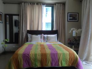 um quarto com uma cama colorida e uma janela em Love This Place em Manila