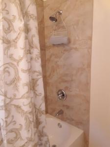 baño con cortina de ducha y bañera en Secret Garden Inn & Cottages en Santa Bárbara