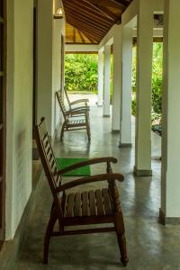two wooden chairs sitting on the porch of a house at Sakura Villa Bentota in Bentota