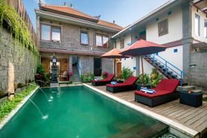 une maison dotée d'une piscine avec des chaises et un parasol dans l'établissement Hartaning House by Pramana Villas, à Ubud