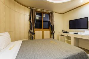 Incheon Airport Hotel في انشيون: غرفة نوم بسرير وتلفزيون بشاشة مسطحة