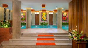a lobby with a staircase and a pool with paintings at Ta Prohm Hotel & Spa in Siem Reap