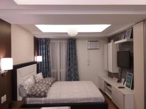 um pequeno quarto com uma cama e uma televisão em Abreeza Place Tower1 by Chriza em Davao