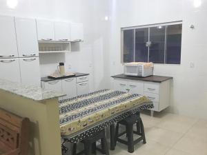 uma cozinha com armários brancos e um banco em Casa temporada Aroeira em Olímpia