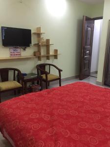 a bedroom with a red bed with chairs and a television at Ruby Hostel in Ha Giang