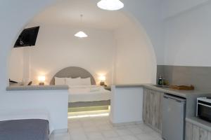 a white bedroom with a bed and a kitchen at Anna's in Karterados
