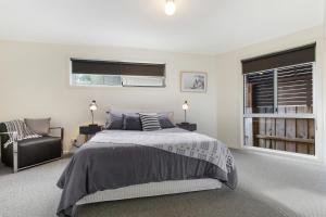 a bedroom with a bed and a chair and a window at Lake House in Lake Tyers