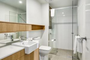 La salle de bains est pourvue de toilettes, d'un lavabo et d'une douche. dans l'établissement Vine Apartments South Brisbane, à Brisbane