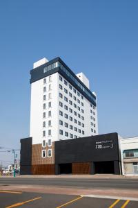 New Tomakomai Prince Hotel NAGOMI في توماكوماي: مبنى أبيض طويل عليه علامة