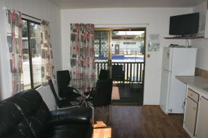 a living room with a black leather couch and a kitchen at Ingenia Holidays Shoalhaven Heads in Shoalhaven Heads