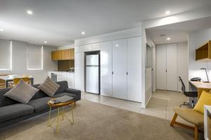 a living room with a gray couch and a kitchen at Vine Apartments South Brisbane in Brisbane