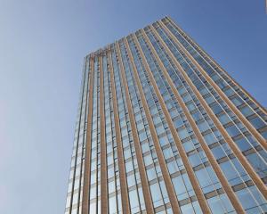 um edifício de vidro alto com um céu azul ao fundo em Hyatt Regency Jinan em Jinan
