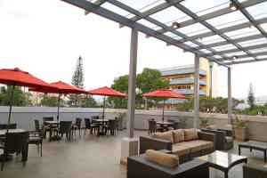 um pátio com mesas, cadeiras e guarda-sóis vermelhos em Hyatt Place Tegucigalpa em Tegucigalpa