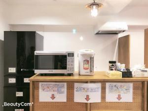 a kitchen with a counter with a microwave and a counter top at Guest House Siesta in Tokyo