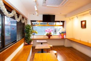 ein Restaurant mit zwei Tischen und einem Fenster mit Blumen in der Unterkunft Guest House Siesta in Tokio