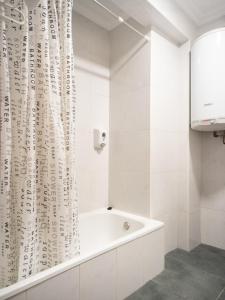 Baño blanco con bañera y cortina de ducha en Hostal Uría, en Salamanca