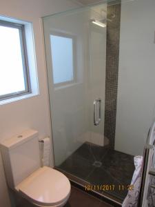 a bathroom with a toilet and a glass shower at Castor Bay Homestay in Auckland