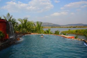 una persona en una piscina en un cuerpo de agua en Fazlani Natures Nest- The Wellness Retreat, en Lonavala