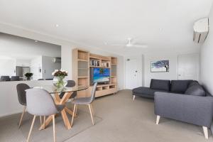 ein Wohnzimmer mit einem Tisch, Stühlen und einem Sofa in der Unterkunft Wharf Lodge River View Apartment in Maroochydore