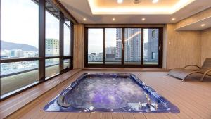 een hot tub in een kamer met ramen bij GnB Hotel in Busan