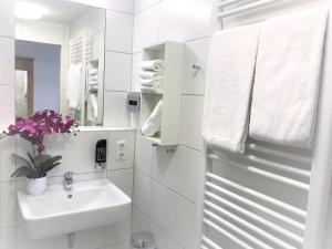 ein weißes Badezimmer mit einem Waschbecken und einem Spiegel in der Unterkunft HHotel Augsburg in Augsburg