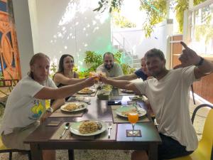 a group of people sitting around a table eating food at Moodhu Surf House in Himmafushi