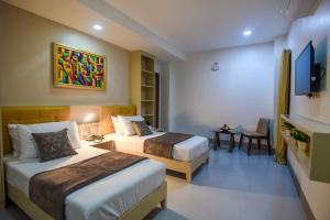 a hotel room with two beds and a tv at ETT HomeTel in Kalibo