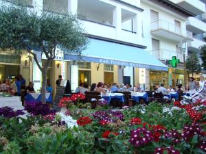Leute sitzen an Tischen in einem Restaurant mit Blumen in der Unterkunft Hotel Blue Marine in Lignano Sabbiadoro