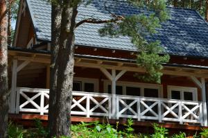 une maison avec une clôture blanche devant elle dans l'établissement Domki Kaszuby - jezioro las i zoo w Szarlocie, à Kościerzyna