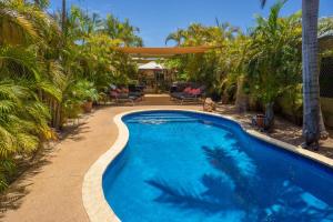 a swimming pool in a yard with palm trees at Ningaloo Lodge Exmouth in Exmouth