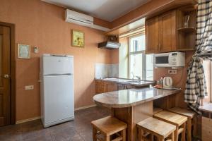 a kitchen with a white refrigerator and wooden cabinets at Apartments on Isaakievskaya in Saint Petersburg