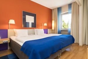 a bedroom with a large bed with an orange wall at ProfilHotels President in Norrköping