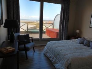 a bedroom with a bed and a chair and a large window at La Naturelle 119 in Wimereux