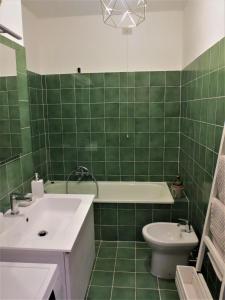 a green tiled bathroom with a sink and a toilet at Quarto di Luna in Genova