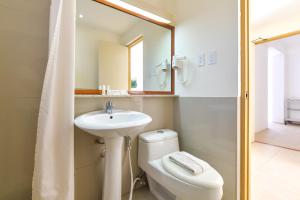 a bathroom with a sink and a toilet and a mirror at Signature Boracay South Beach in Boracay