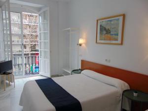 um quarto de hotel com uma cama e uma janela em Hostal El Cairo em Sevilha