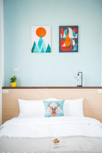 sypialnia z łóżkiem z dwoma obrazami na ścianie w obiekcie D.C. Inn w mieście Magong