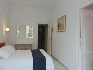 
a bedroom with a white bed and white walls at Hostal El Cairo in Seville
