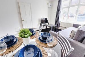 a dining room table with blue plates and wine glasses at Clarence Place in Edgware