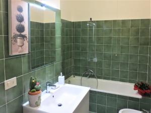 a green tiled bathroom with a sink and a tub at Quarto di Luna in Genoa