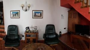 una sala de estar con 2 sillas de cuero negro y una mesa. en B&B the lost Village el Acebuchal, en Frigiliana
