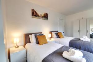 two beds in a bedroom with two lamps and towels at Clarence Place in Edgware