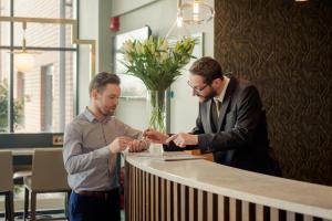 twee mannen die rond een tafel staan te kijken naar een horloge bij The Hoban Hotel Kilkenny in Kilkenny